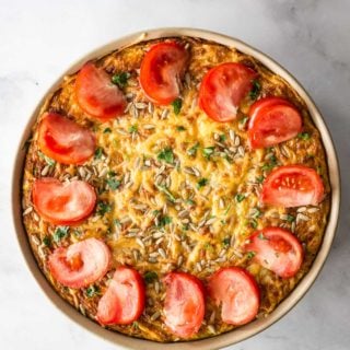 A beautiful gluten free crustless zucchini bacon quiche topped with sliced tomatoes and melted cheese.