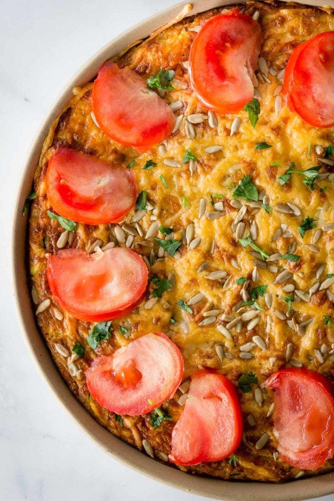 A beautiful gluten free crustless zucchini bacon quiche topped with sliced tomatoes.