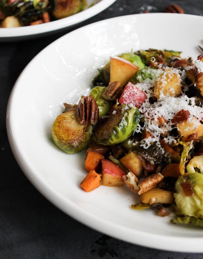 Pan-Roasted Brussels Sprouts with grated parmesan served on a white dish.