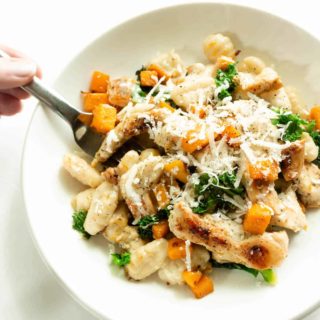 Sliced grilled chicken with gnocchi, sautéed butternut squash, and kale in a creamy sauce topped with grated parmesan.