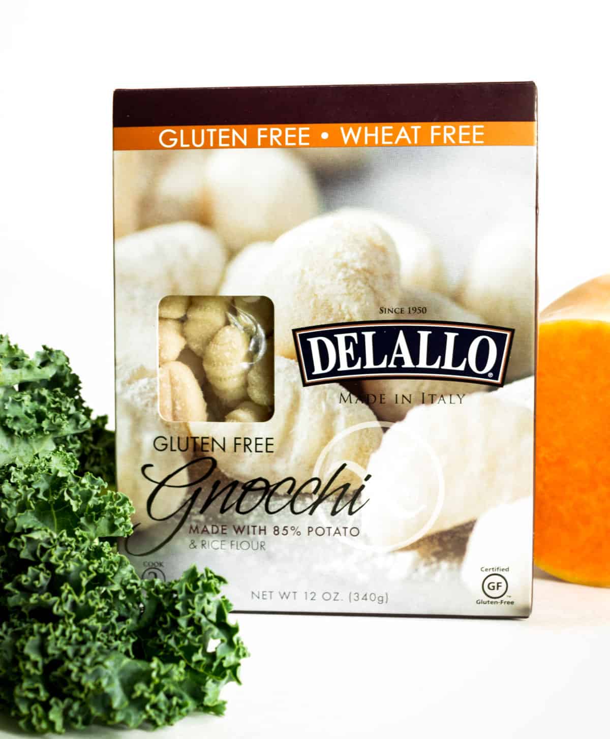 A box of gluten free Delallo brand gnocchi sits next to some green kale and a butternut squash.