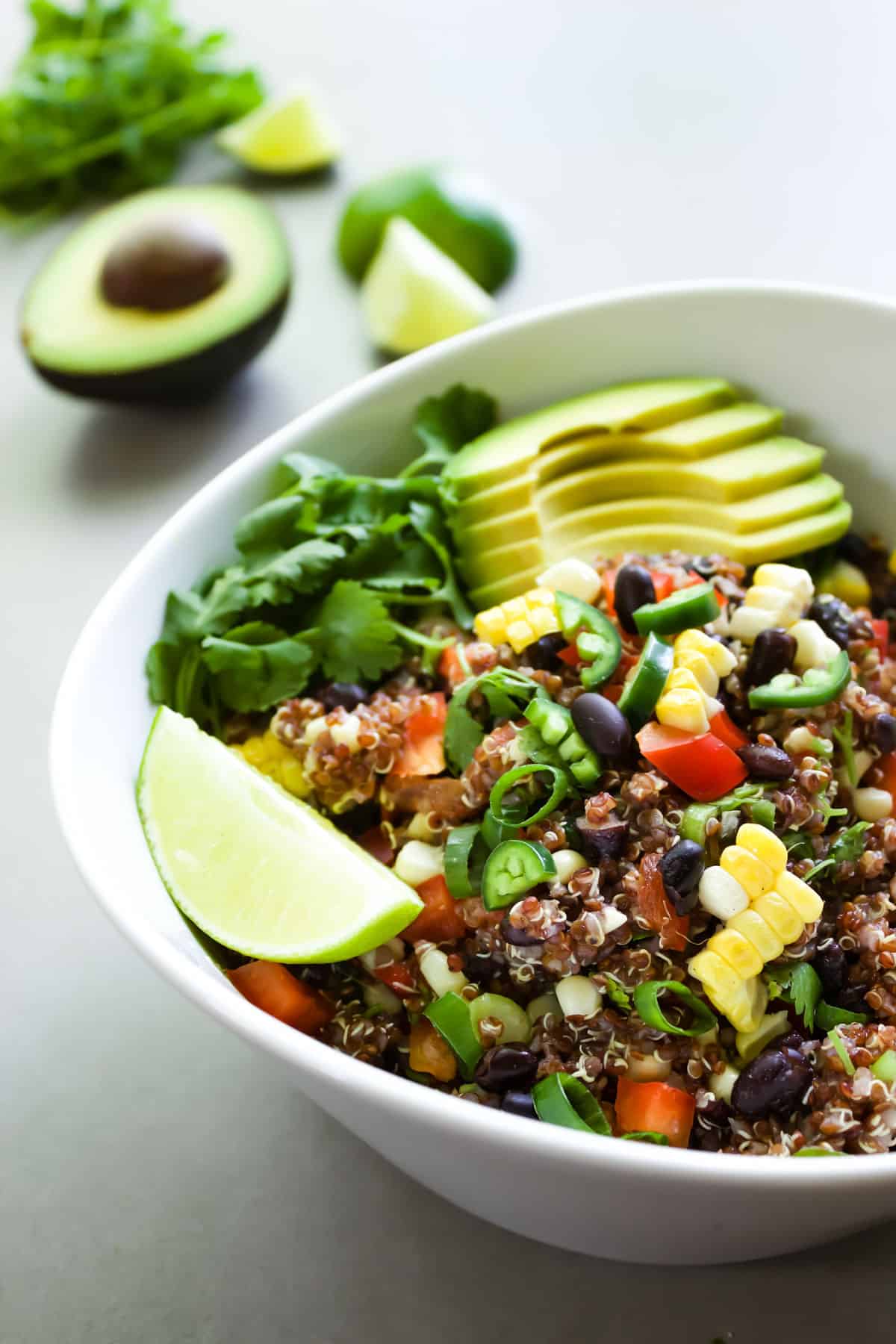 A bowl of spicy red quinoa salad served with lime and avocado.