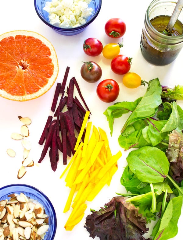 Simple ingredients for the green salad with beets and grapefruit are laid out. A small mason jar of balsamic vinaigrette is included.