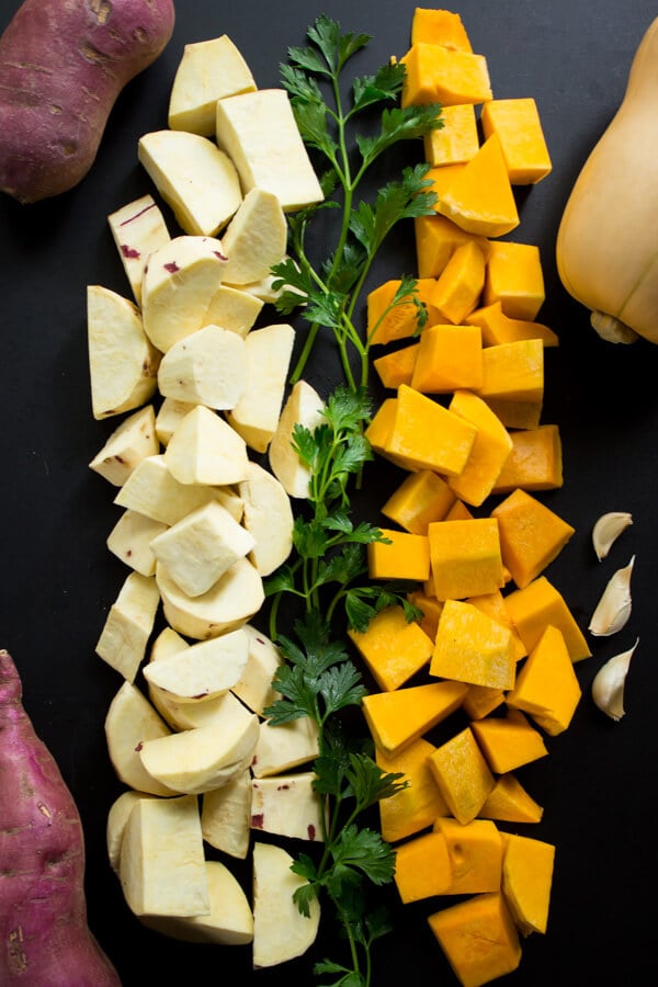 Chopped Japanese sweet potatoes and chopped butternut squash with sprigs of parsley and a few garlic cloves.