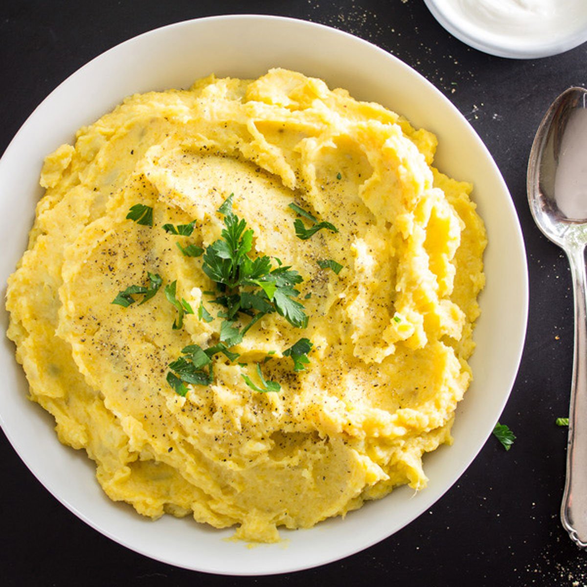 Creamy mashed potatoes and butternut squash in a white bowl.