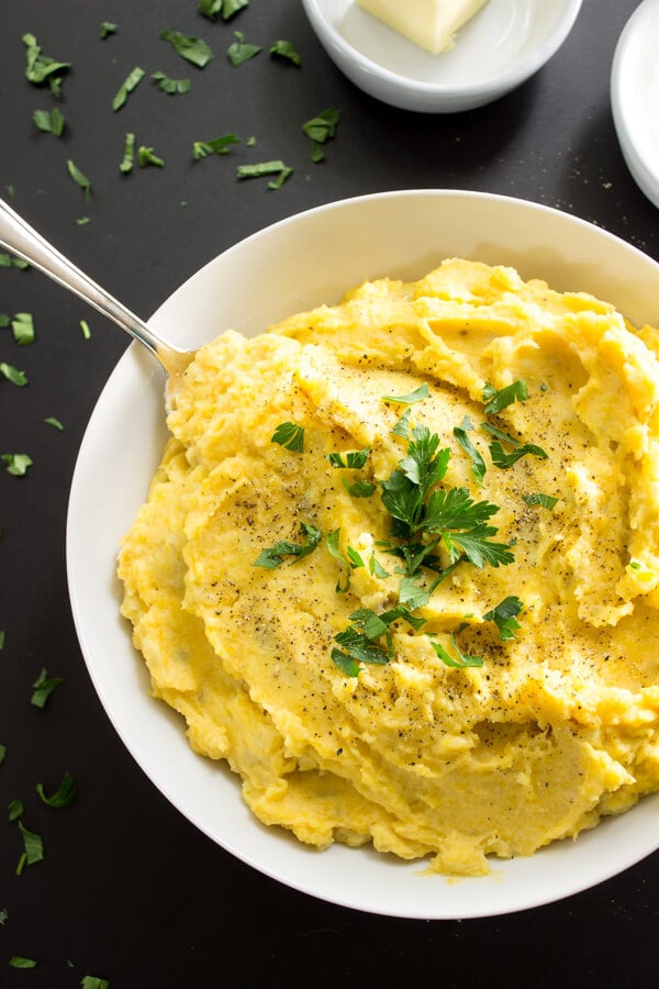 A big bowl of dreamy mashed potatoes with a silver spoon ready to dig in.