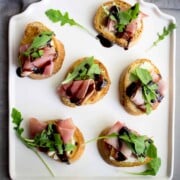 Fig, prosciutto and port salut cheese crostini are topped with a drizzle of balsamic reduction.