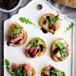 Fig, prosciutto and port salut cheese crostini are topped with a drizzle of balsamic reduction.