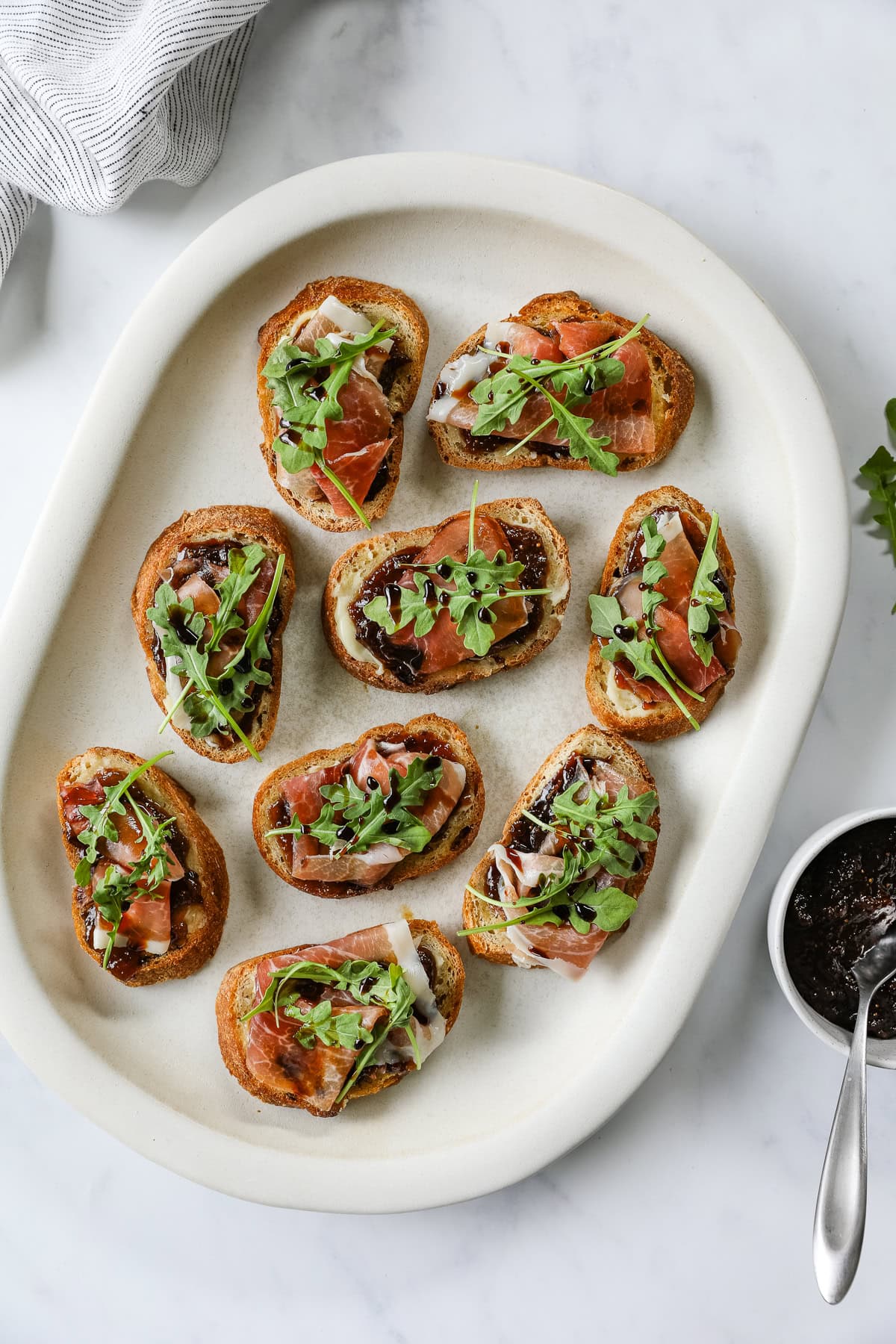 Fig and prosciutto crostini topped with arugula and balsamic reduction.
