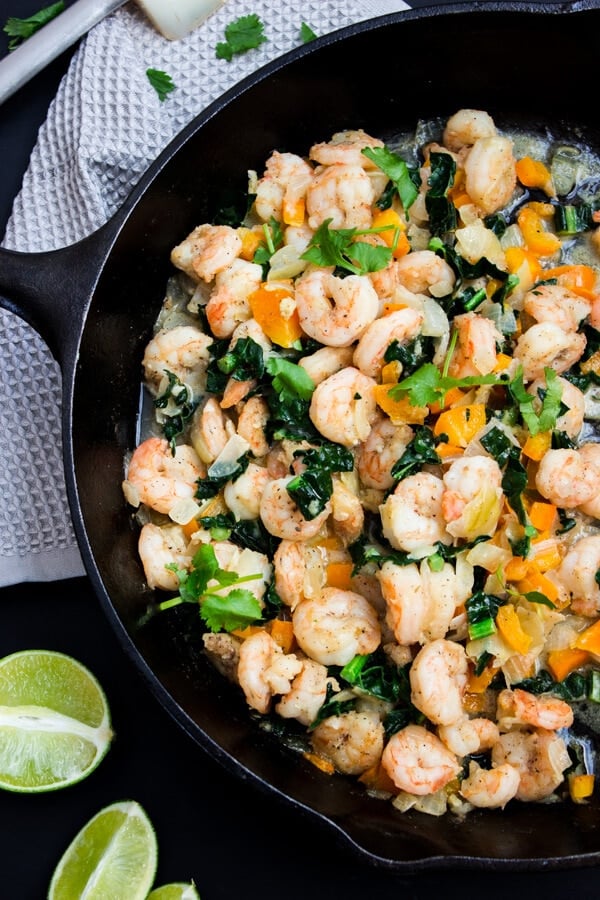 A cast iron skillet cooked taco filling consisting of shrimp, orange bell peppers, sautéed kale, garlic and butter. Topped with fresh Italian parsley.