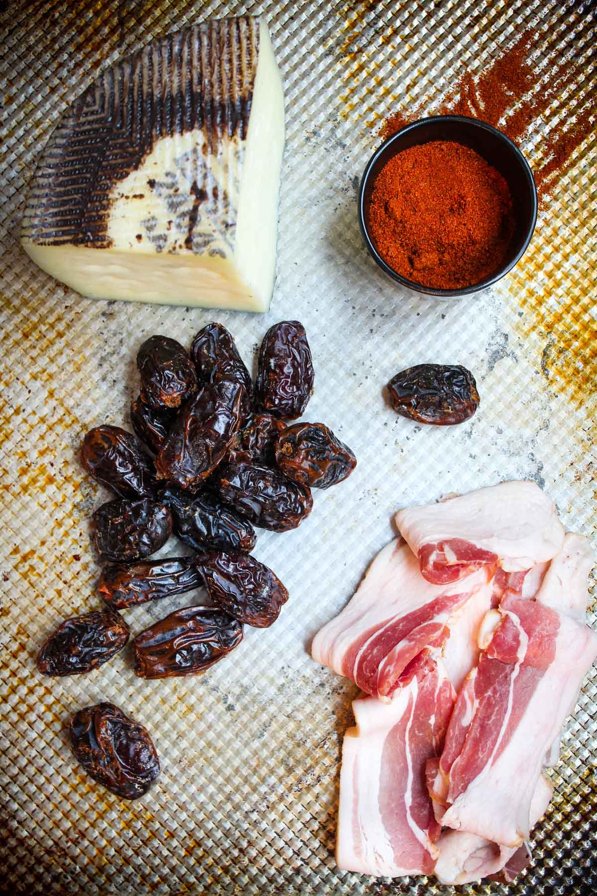 Ingredients for chili bacon wrapped dates are set out. Only four ingredients: Manchego cheese, chili powder, bacon, and dates.