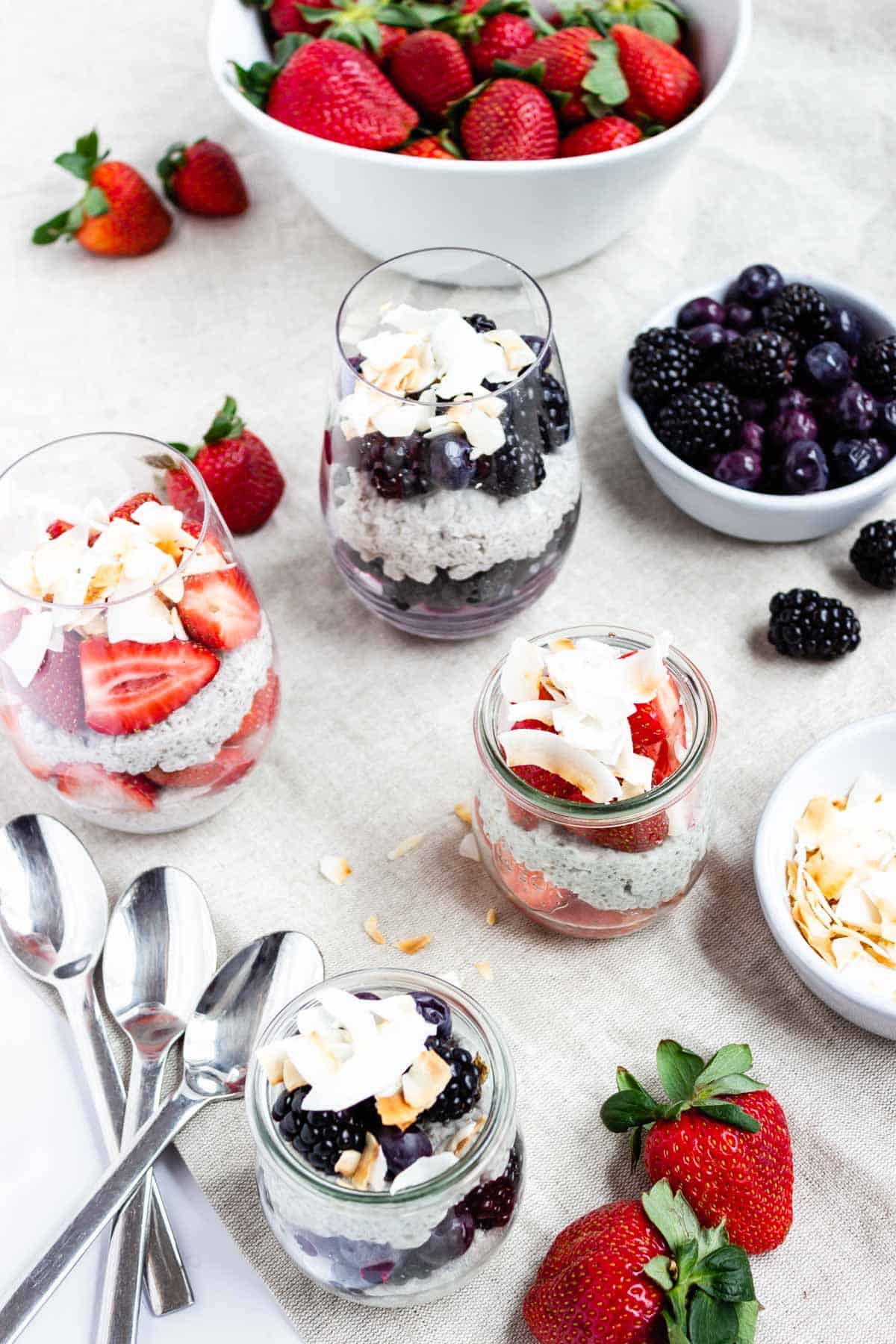Several jars of coconut chia parfaits using strawberries, blueberries, and blackberries. Topped with toasted coconut.