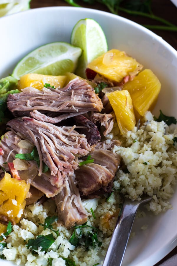 A close-up view of a plate of slow cooker pineapple pulled pork with cauliflower rice and guacamole.