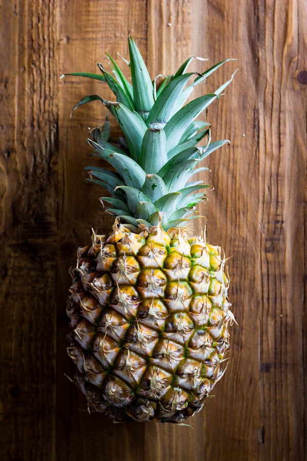 A pineapple laying on a rustic wood background.