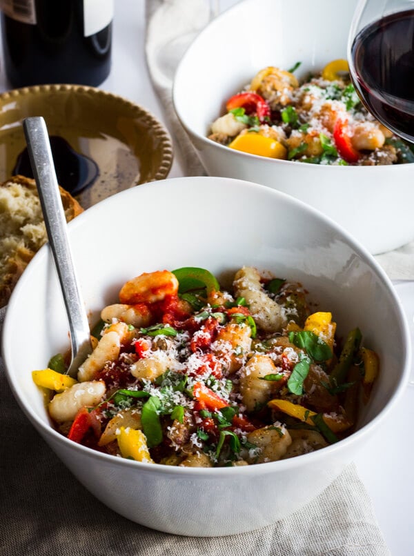 A bowl of gnocchi marinara with Italian sausage and tri-colored bell peppers.