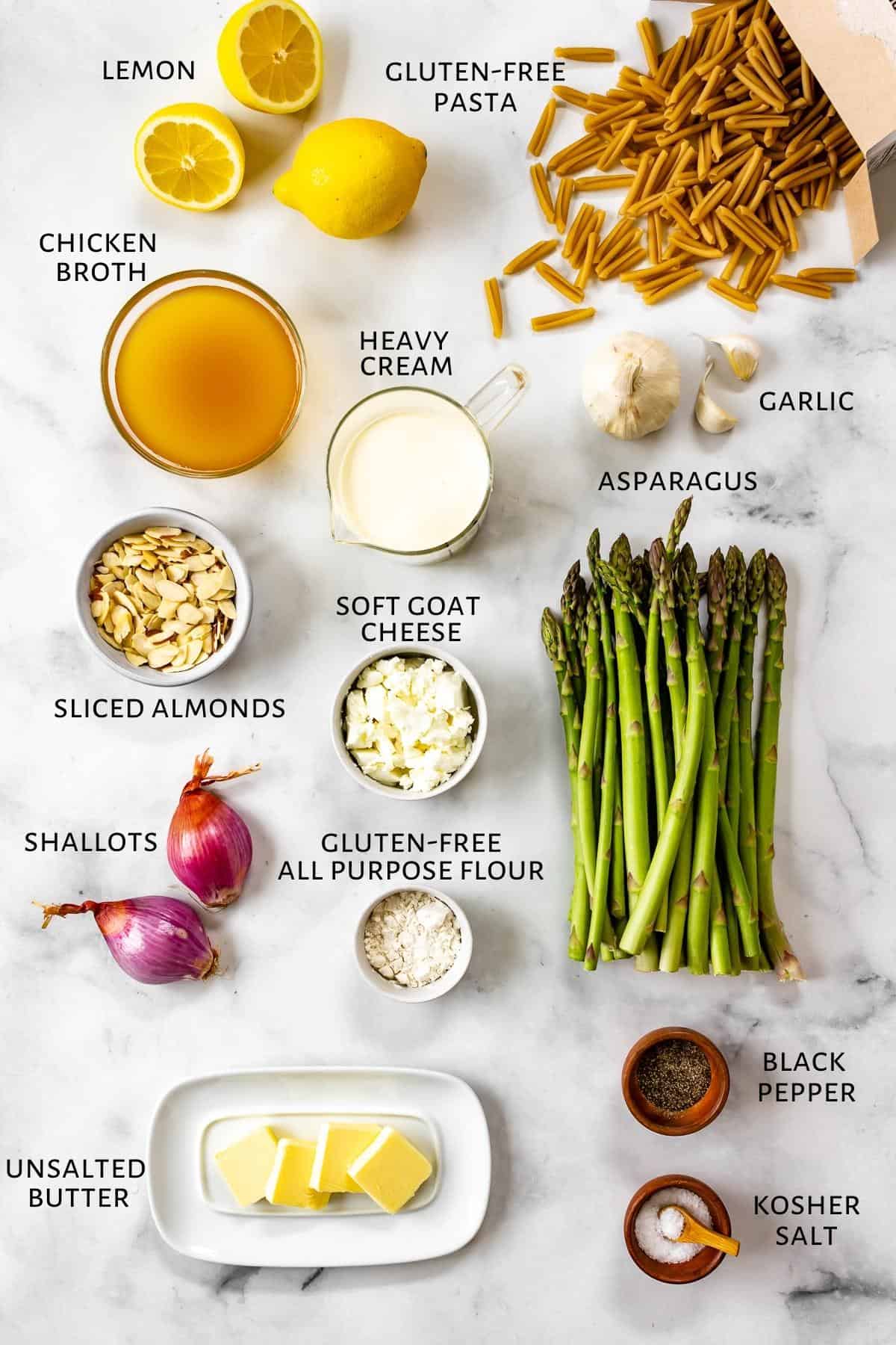 Ingredients for lemon asparagus pasta are spread out on a marble counter.