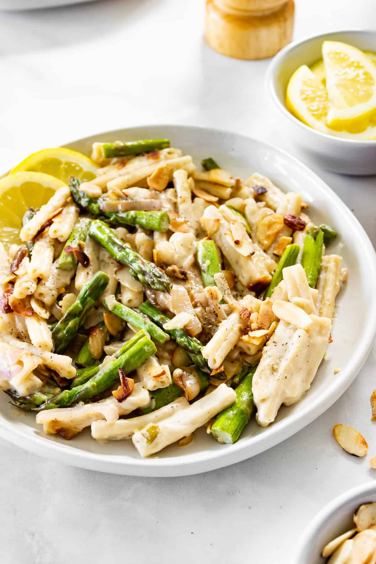 A plate of lemon pasta topped with sautéed asparagus, shallots, and toasted almonds.