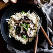 A bowl of creamy risotto topped with sautéed mushrooms.