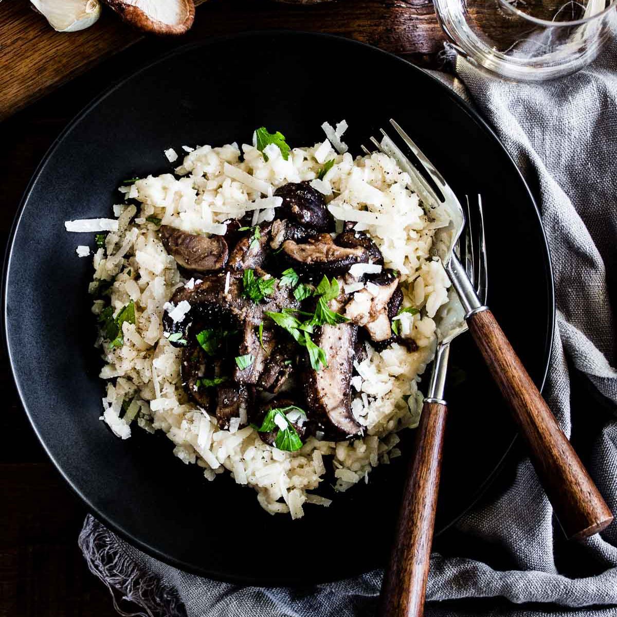 A bowl of creamy risotto topped with sautéed mushrooms.