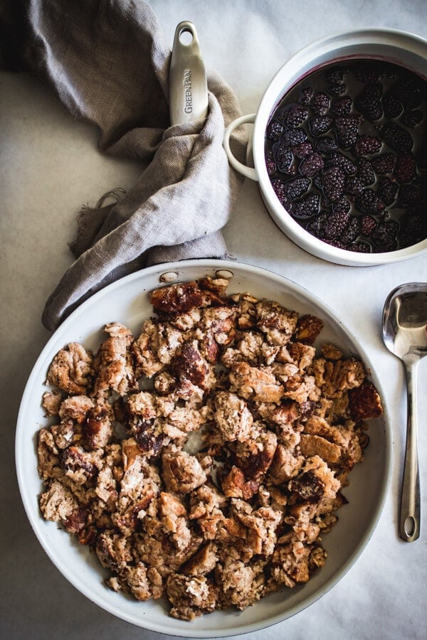 A frying pan with fluffy shredded Kaiserschmarrn. A serving utensil and a baking dish of roasted Oregon Marionberries sits nearby.