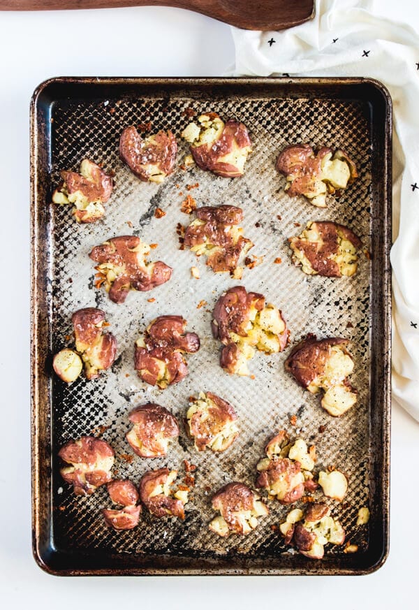 A baking sheet with crispy smashed baby red potatoes sprinkled with Maldon flaked sea salt.