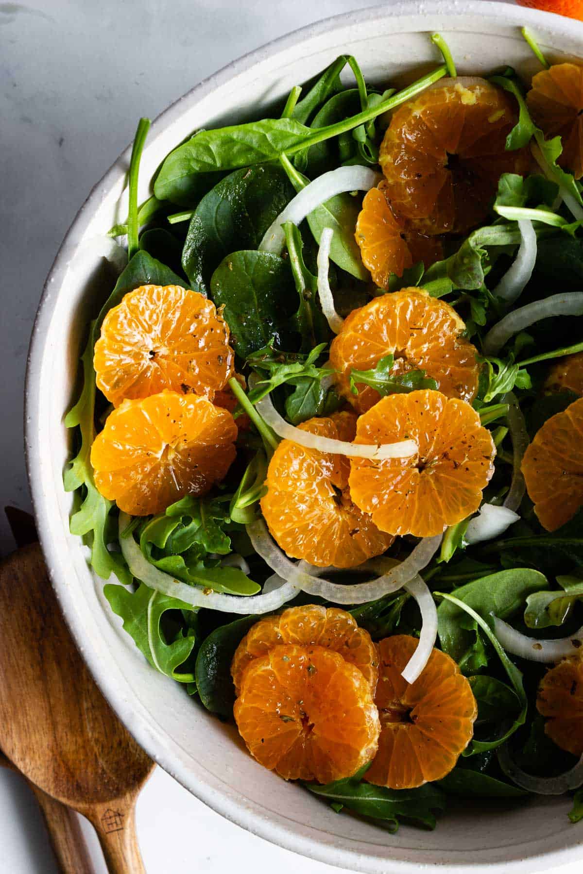 Mandarine slices are arranged on a green salad.