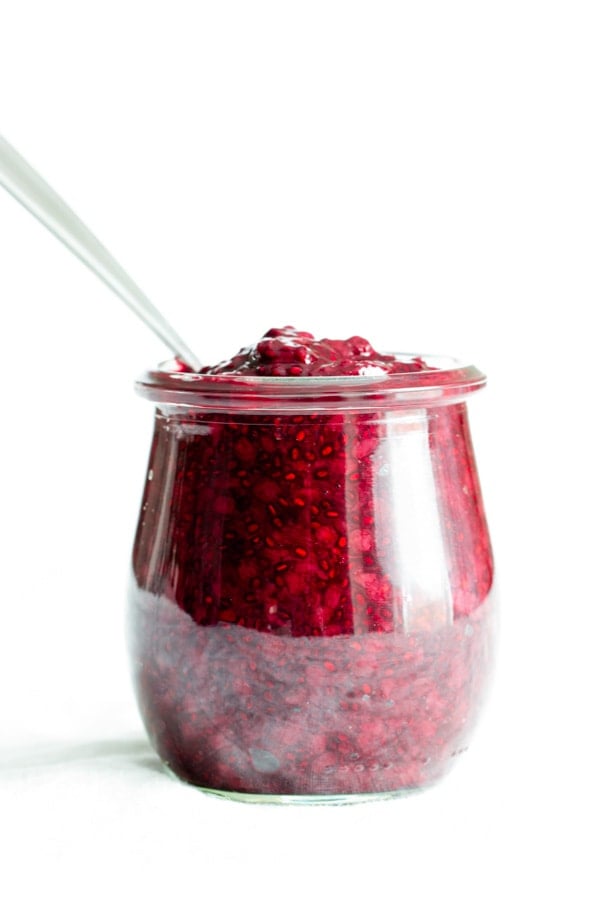 A small Weck jar of blackberry chia jam made with Oregon Marionberry blackberries. A spoon is dipped into the jar.