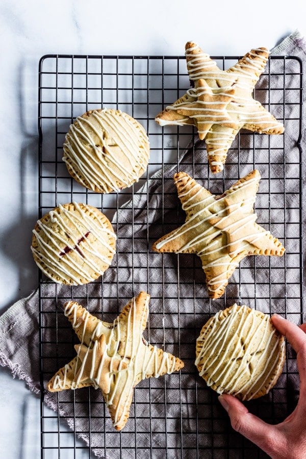 Circle and star-shaped raspberry hand pies are cooling on wire rack.