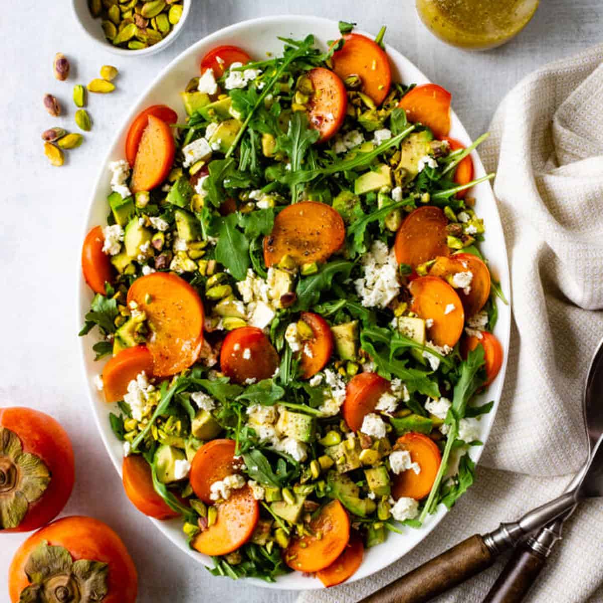 A persimmon arugula salad topped with pistachios, feta, and lemon vinaigrette.