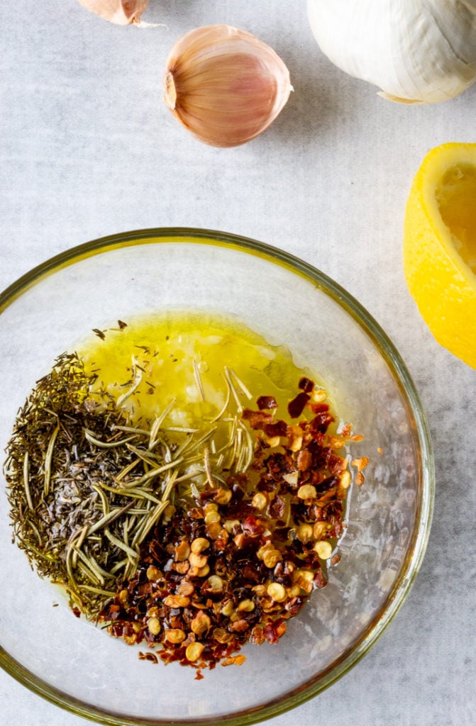 Lemon, garlic, olive oil, and herbs are prepared together in a bowl to be tossed with the vegetables prior to roasting.