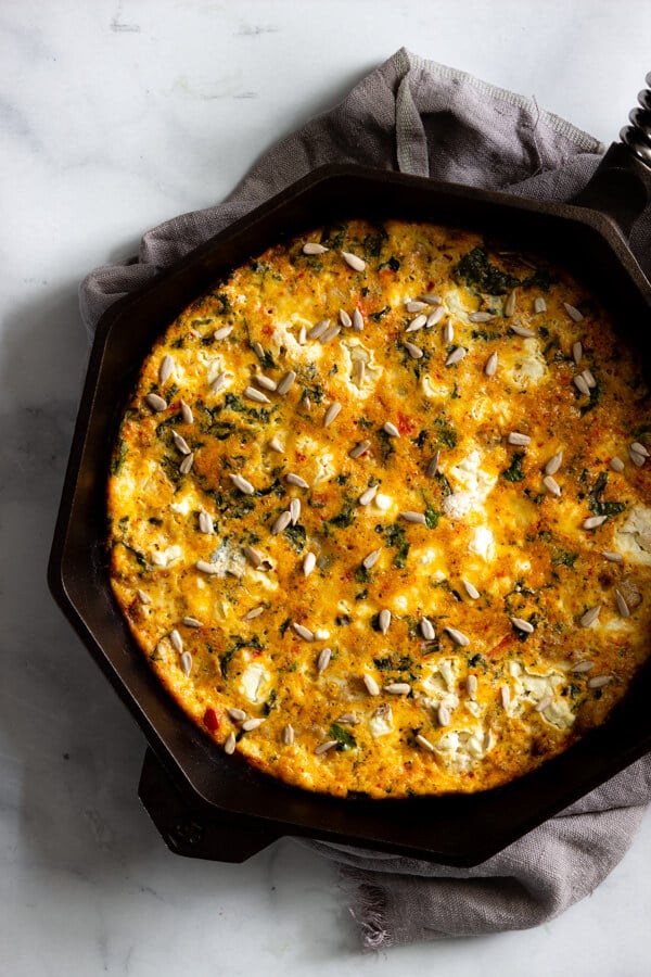 A sausage, kale, and sun-dried tomato pesto frittata baked in a cast iron skillet.