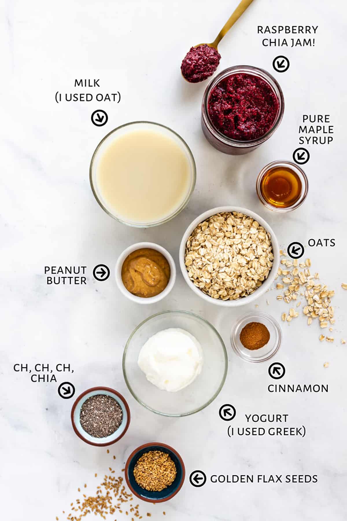 All of the ingredients for the overnight oats are setout in little bowls on a white countertop.