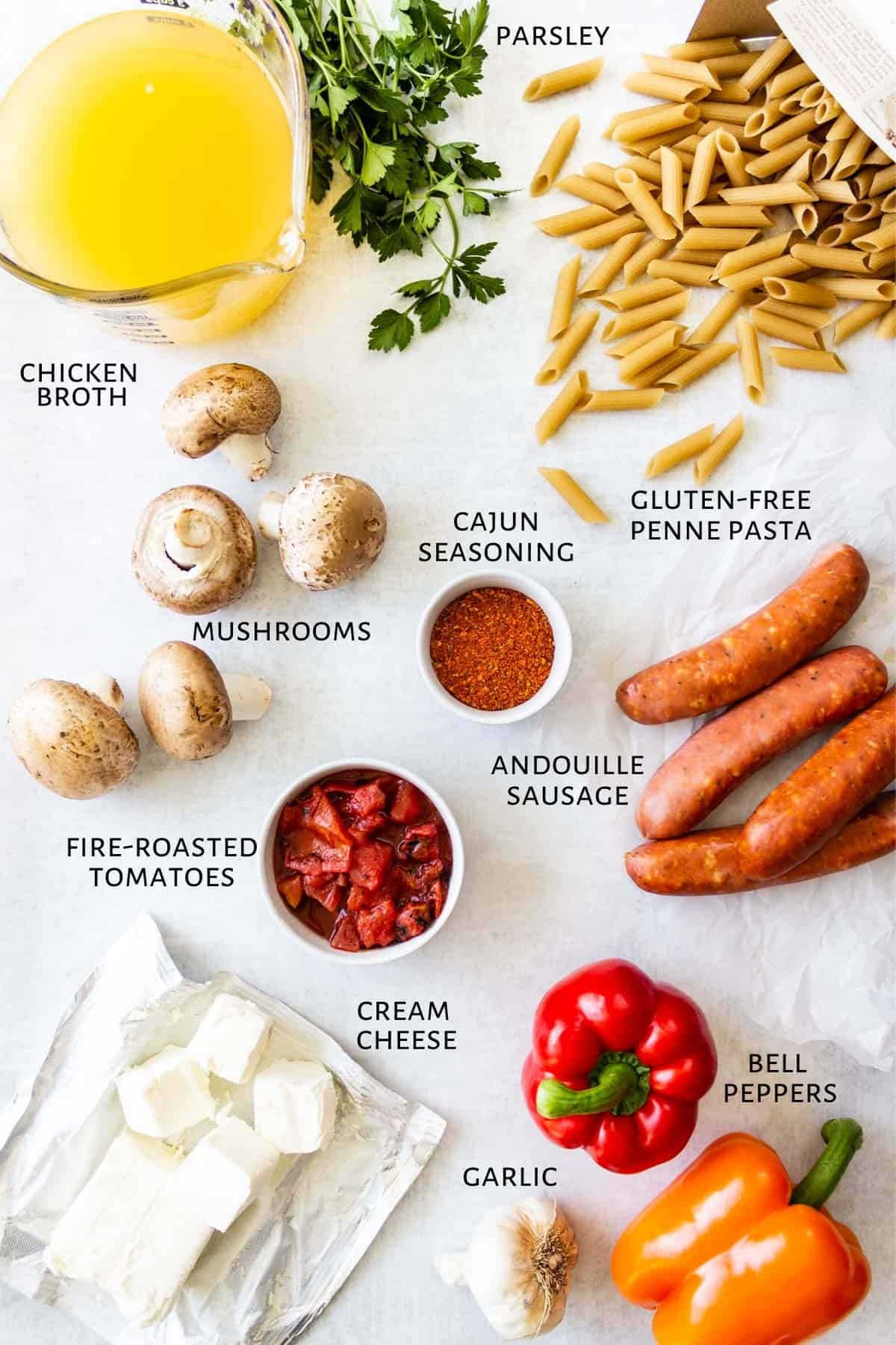 Ingredients for cajun creamy sausage pasta are spread out on a marble counter.