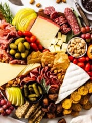 A charcuterie board loaded with cheeses, meats, nuts, olives, crackers, and fruit.