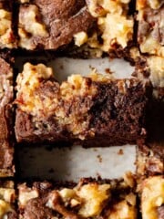 A brownie is standing on its side among a pan of brownies.