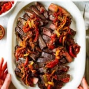A flank steak is perfectly cooked, sliced into thin strips, and topped with peperonata.