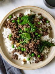 Rice is topped with ginger ground beef with peas and spinach.