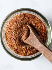 A little wooden spoon is scooped into a jar of homemade Cajun seasoning mix.