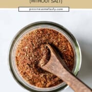 A little wooden spoon is scooped into a jar of homemade Cajun seasoning mix.