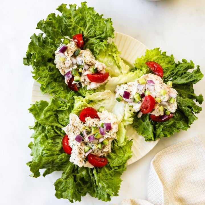 Three tzatziki chicken lettuce wraps served on a white plate.