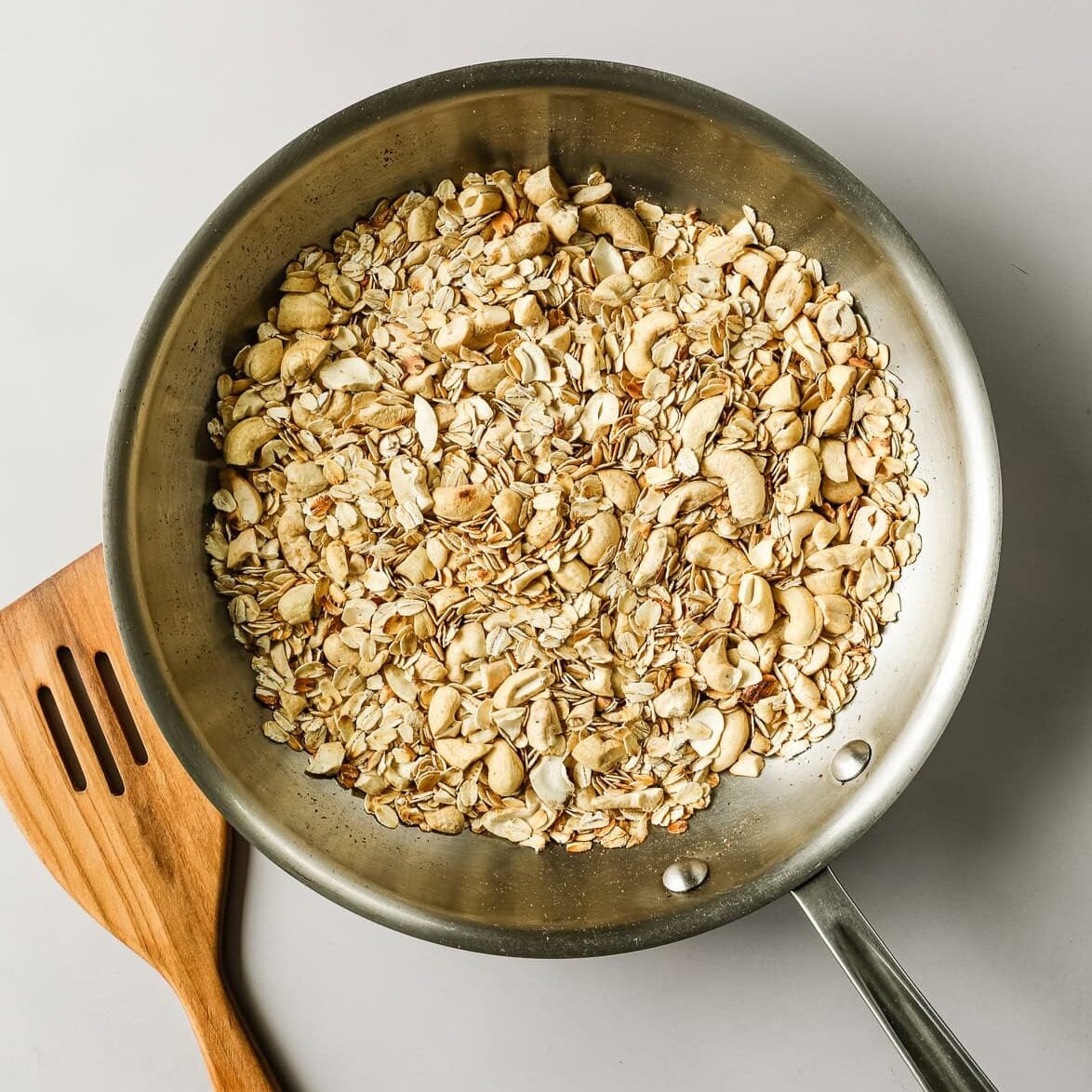 Oats and cashews toasted in a skillet.