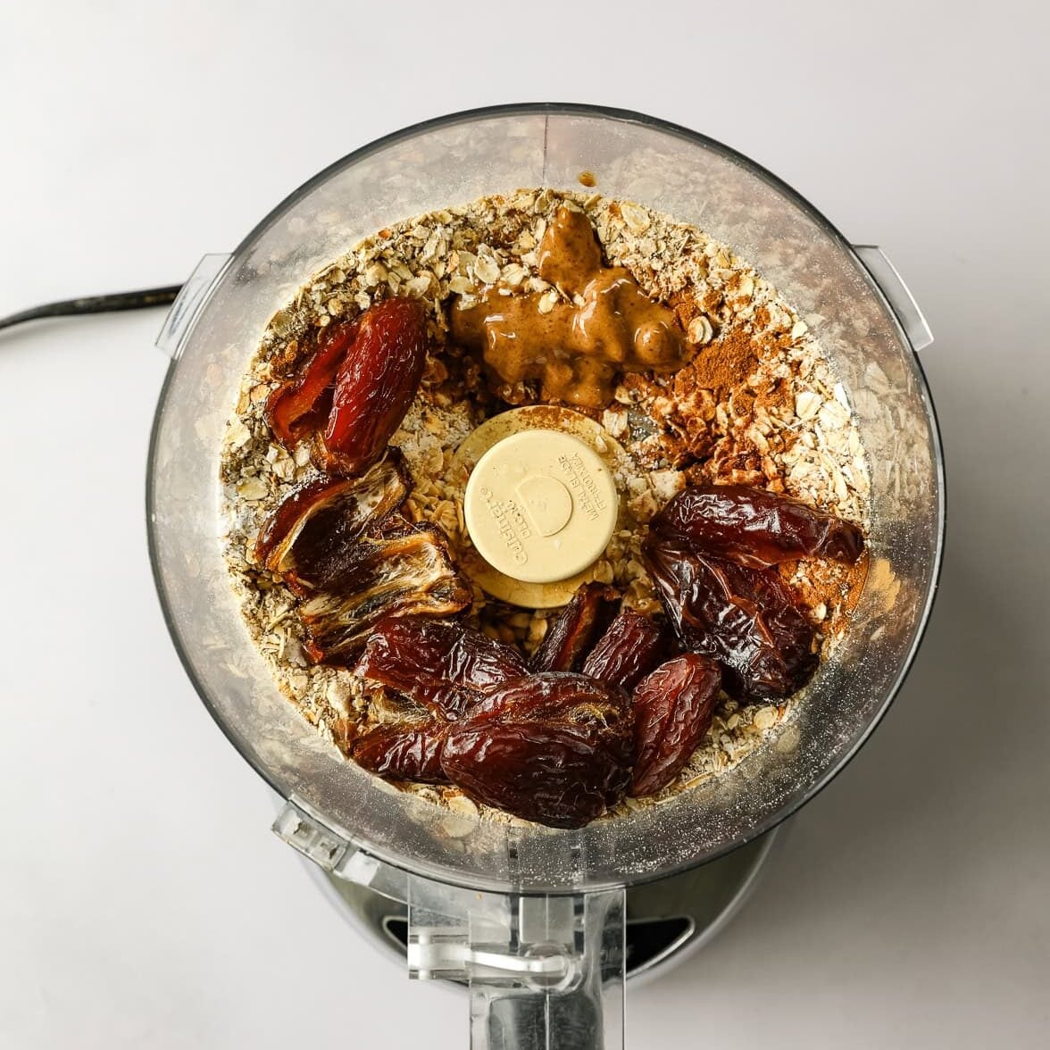 Ingredients for no-bake chocolate date energy bars are added to a food processor.