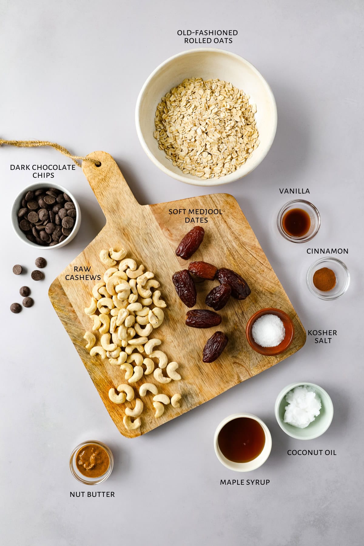 Ingredients for no-bake chocolate dater energy bars are laid out on a countertop and wooden serving board.