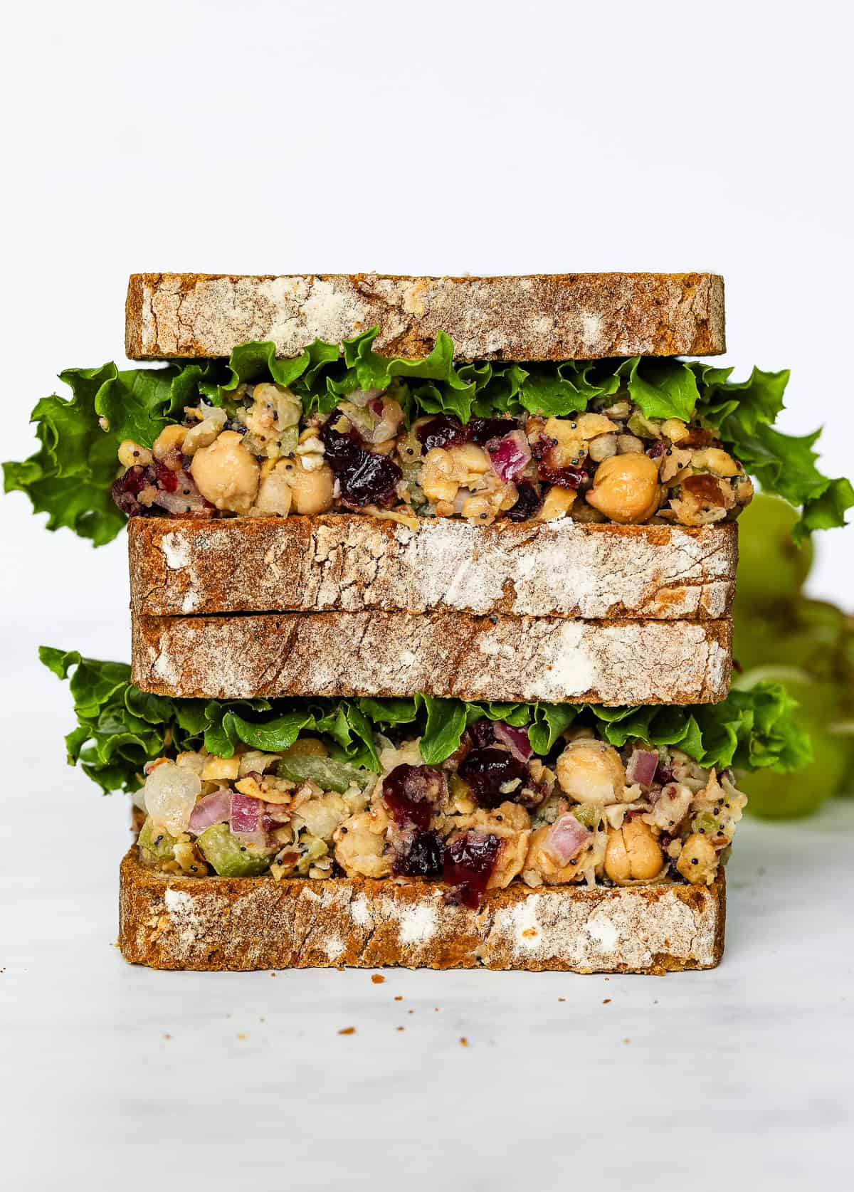 Cranberry pecan chickpea salad is served on a sandwich with green lettuce.