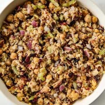 A close up of cranberry pecan chickpea salad in a white bowl.