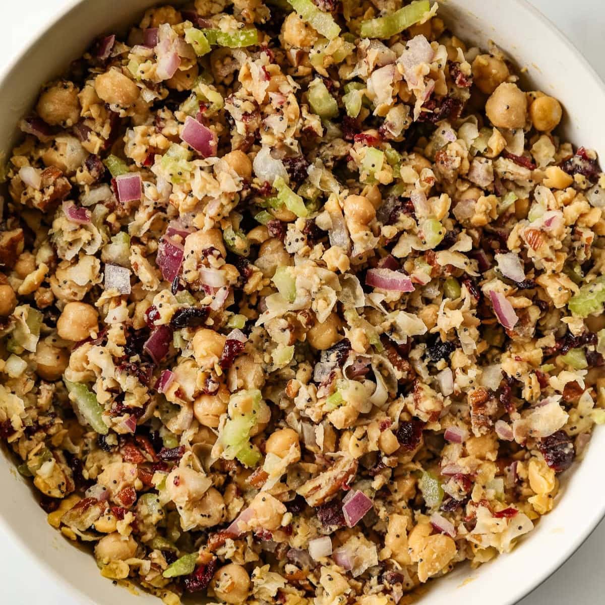 A close up of cranberry pecan chickpea salad in a white bowl.