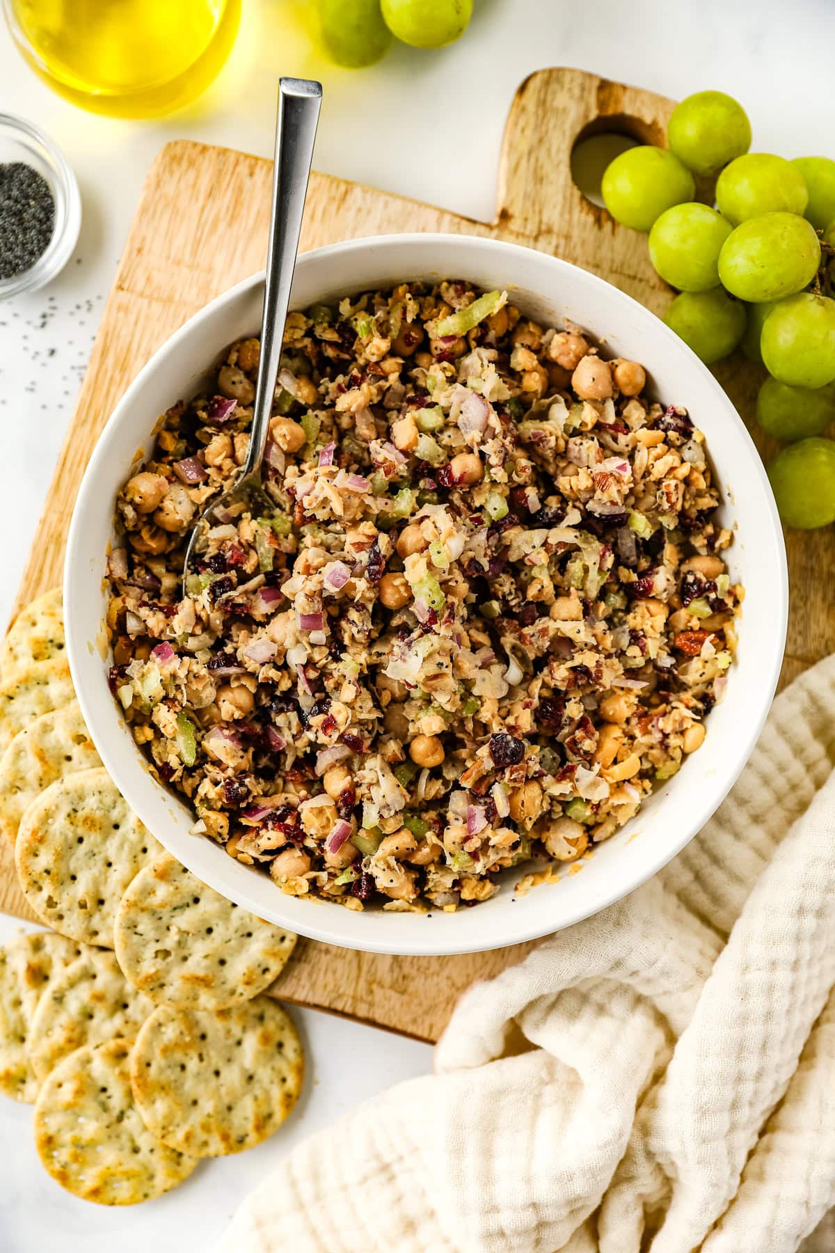 Cranberry pecan chickpea salad in a bowl served with crackers and grapes.