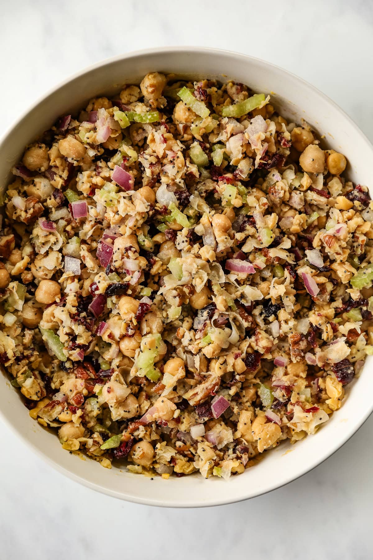A close up of cranberry pecan chickpea salad in a white bowl.