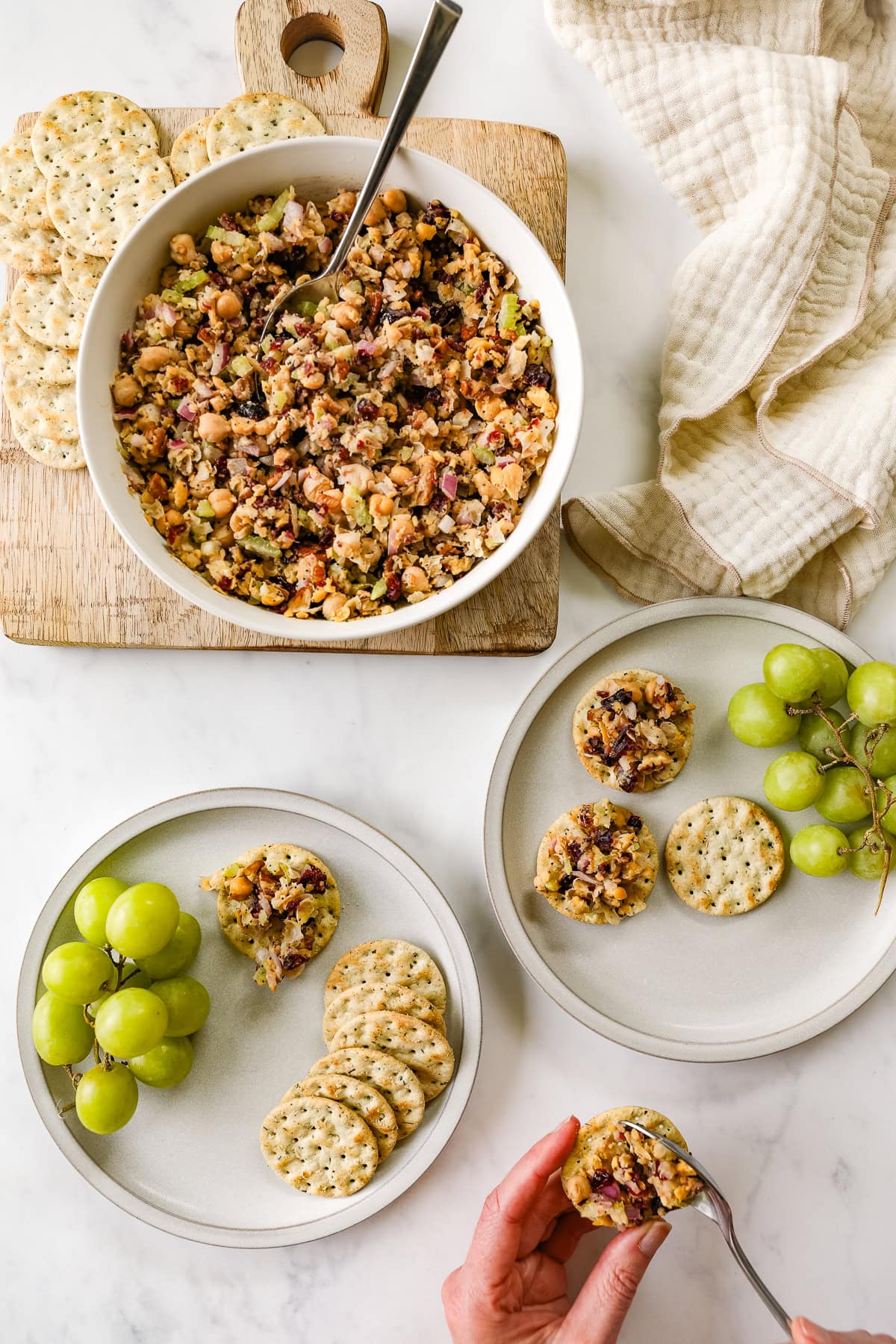 Cranberry pecan chickpea salad is served on crackers with a side of green grapes.
