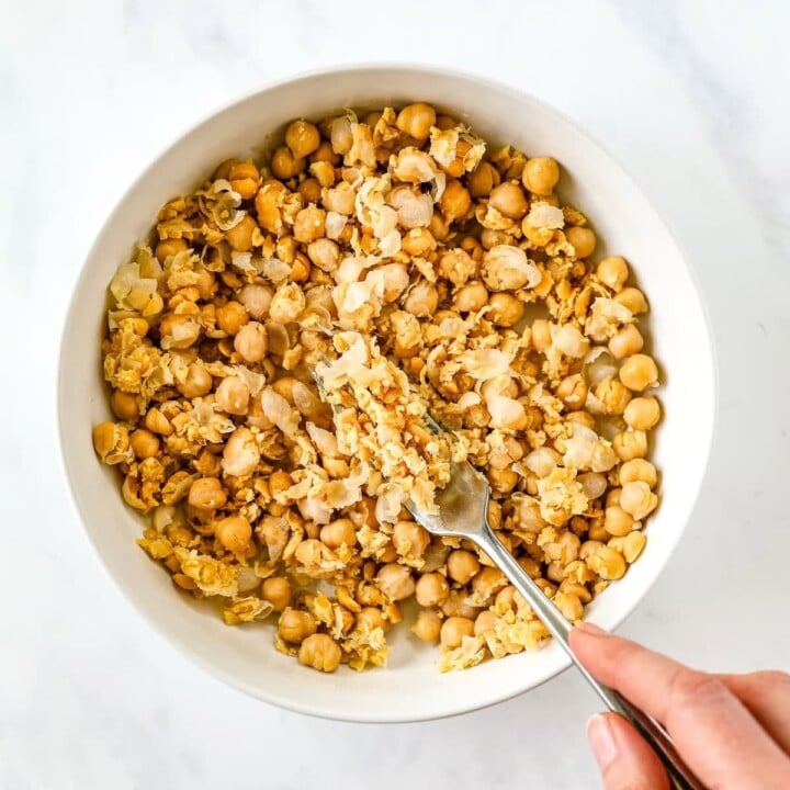 A fork is smashing chickpeas.